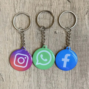 NFC Keychain featuring Instagram, WhatsApp, and Facebook logos on a wooden surface for instant social media sharing.