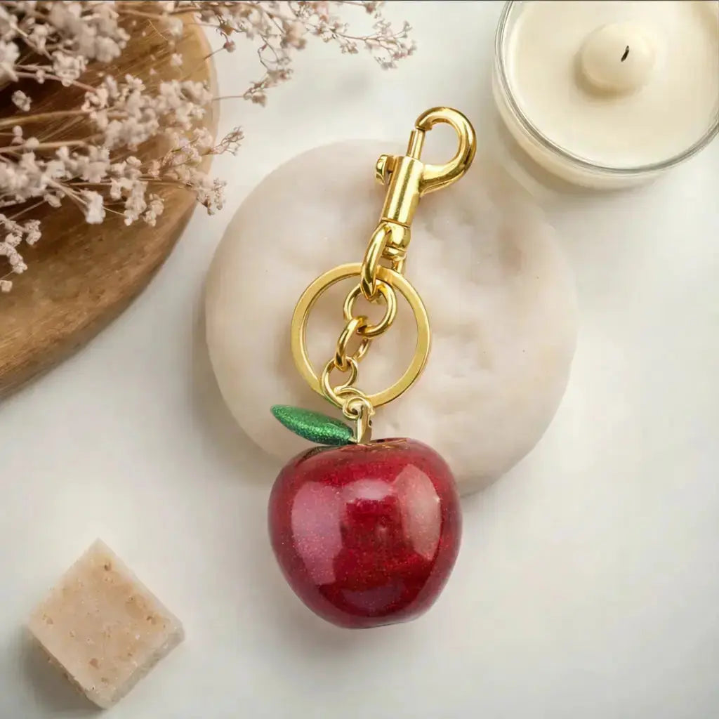 Hypes Inventory Apple-shaped keychain bag charm attached to a handbag, adding a cute and aesthetic accessory for women.