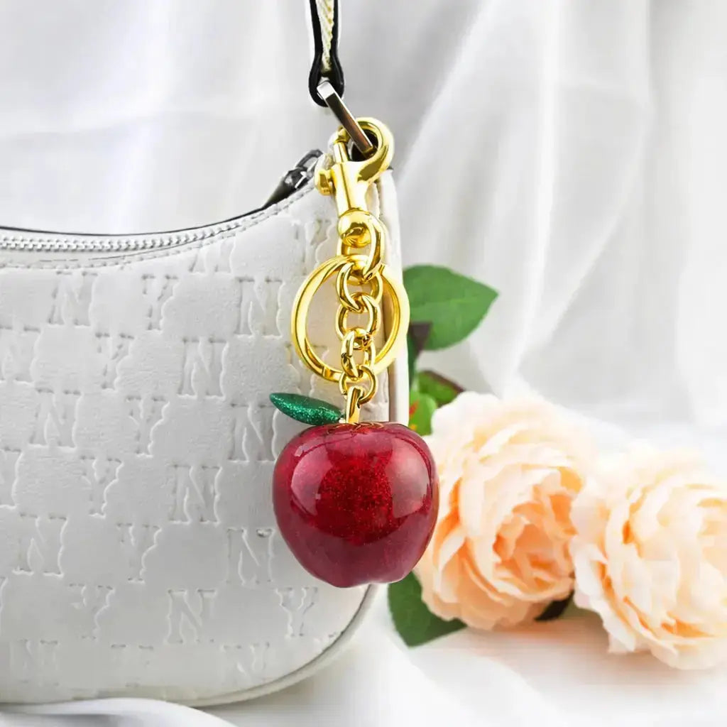 Hypes Inventory Apple-shaped keychain bag charm attached to a handbag, featuring a cute and aesthetic accessory for women.
