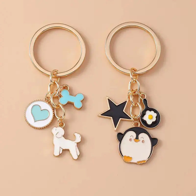 Cute enamel cartoon dog and penguin keychain by Hypes Inventory, featuring heart and star charms for bags and keys.