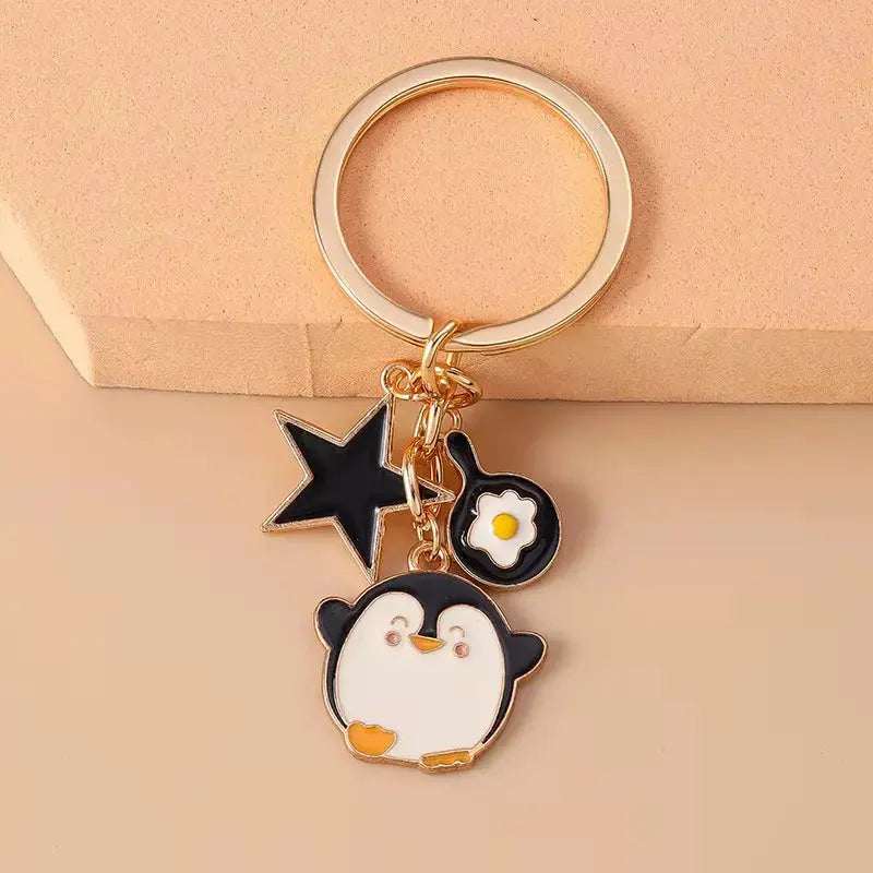 Cute enamel cartoon dog and penguin keychain from Hypes Inventory, ideal for bags, keys, or as a charming gift.