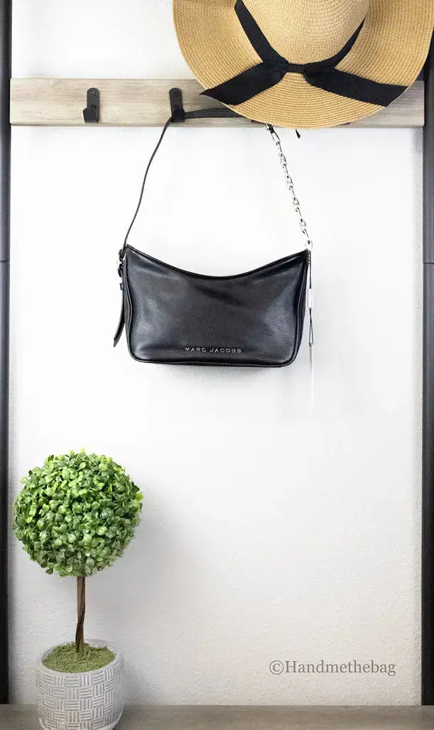 Small black leather Marc Jacobs hobo bag with shoulder strap and minimalist design, featuring subtle brand logo details.