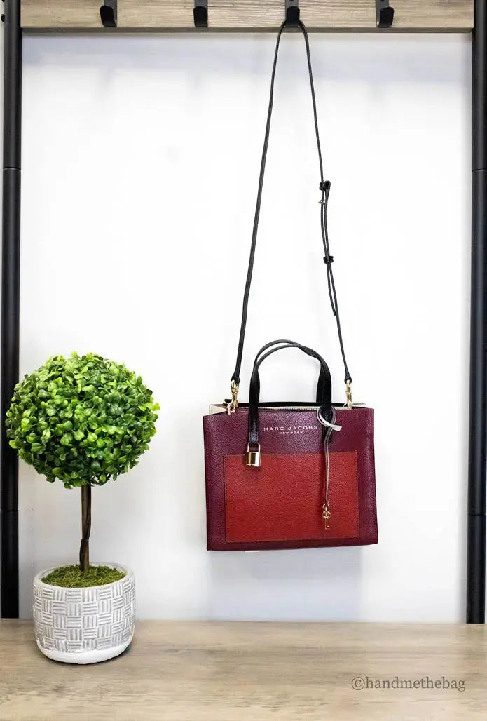 Marc Jacobs Grind Mini leather tote in pomegranate color block, stylish crossbody bag with sleek design and compact size.