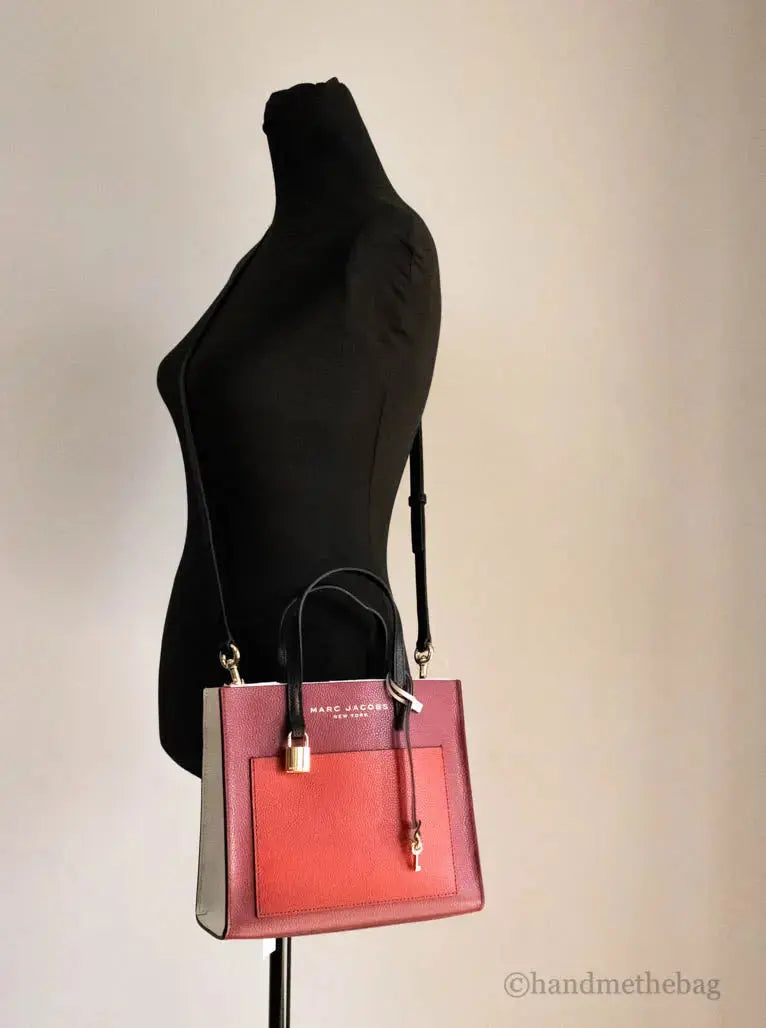Marc Jacobs Grind Mini Leather Tote in pomegranate color block with top handles and adjustable crossbody strap.