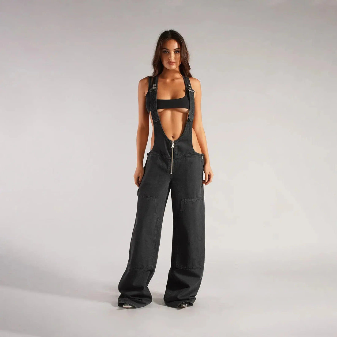 Black Y2K denim overalls for women by Flairé™ with a zip front, loose fit, and front pockets, styled as a casual jumpsuit.